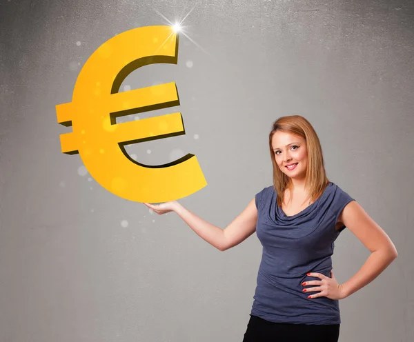 Beautiful girl holding a big 3d gold euro sign — Stock Photo, Image