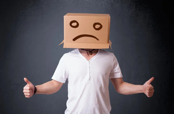 Young man with a brown cardboard box on his head with sad face — Stock Photo, Image