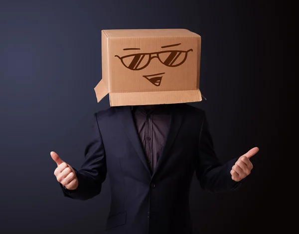 Joven haciendo un gesto con una caja de cartón en la cabeza con sonriente — Foto de Stock