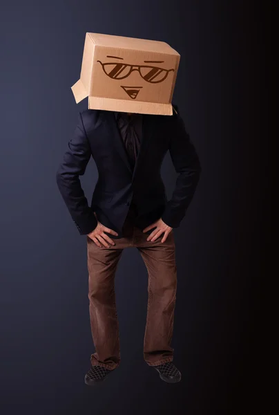 Genç adam smiley ile kafasına bir karton kutu ile el hareketi — Stok fotoğraf