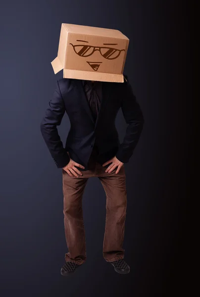 Young man gesturing with a cardboard box on his head with smiley — Stock Photo, Image