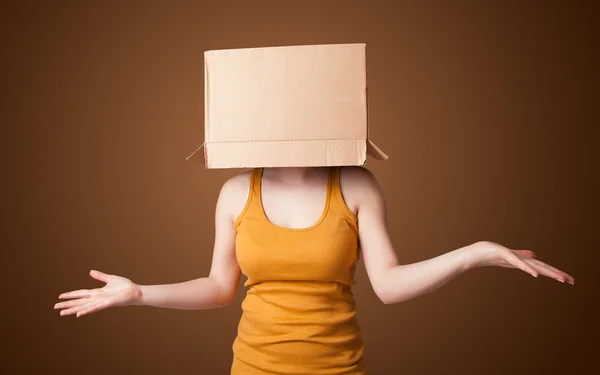 Молодая девушка жестикулирует с картонной коробкой на голове — стоковое фото