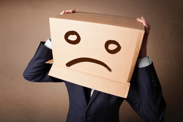 Businessman gesturing with cardboard box on his head with sad fa — Stock Photo, Image