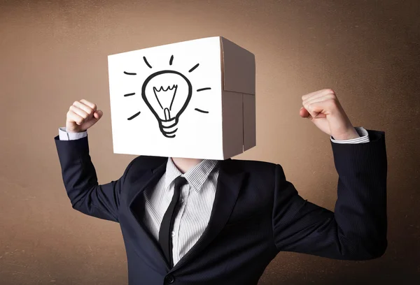 Businessman gesturing with a cardboard box on his head with ligh — Stock Photo, Image