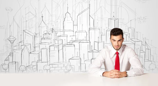 Businessman sitting at the white table with hand drawn buildings — Stock Photo, Image