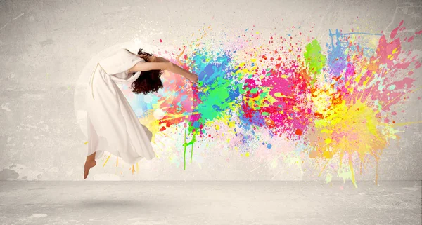 Happy teenager jumping with colorful ink splatter on urban backg — Stock Photo, Image