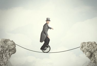 Uçurumlar arasında tekli bisiklet süren cesur bir iş adamı.