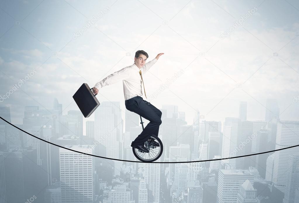 Brave guy riding a monocycle on a rope above cityscape