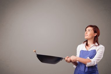 Genç bayan elinde kızartma tavası tutuyor.