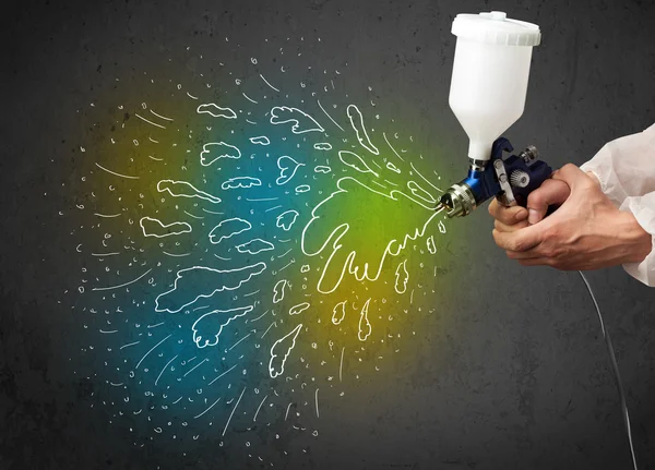 Worker with airbrush gun paints colorful lines and splashes — Stock Photo, Image