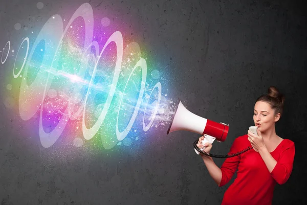 Young girl yells into a loudspeaker and colorful energy beam com — Stock Photo, Image