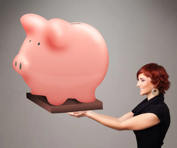 Jovem segurando uma enorme poupança porquinho banco — Fotografia de Stock