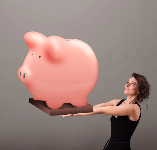 Jovem segurando uma enorme poupança porquinho banco — Fotografia de Stock