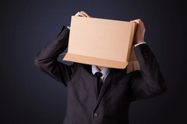Podnikatel gestikuluje s lepenkovou krabicí na hlavě — Stock fotografie