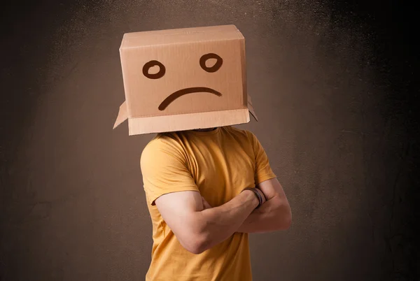 Junger Mann mit braunem Karton auf dem Kopf und traurigem Gesicht — Stockfoto