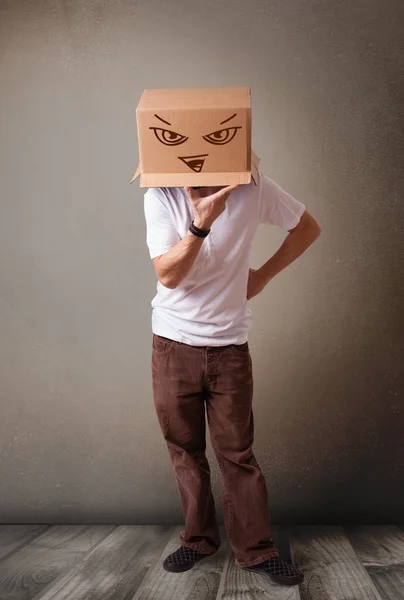 Młody człowiek gestykulacji z karton na głowę z evil f — Zdjęcie stockowe