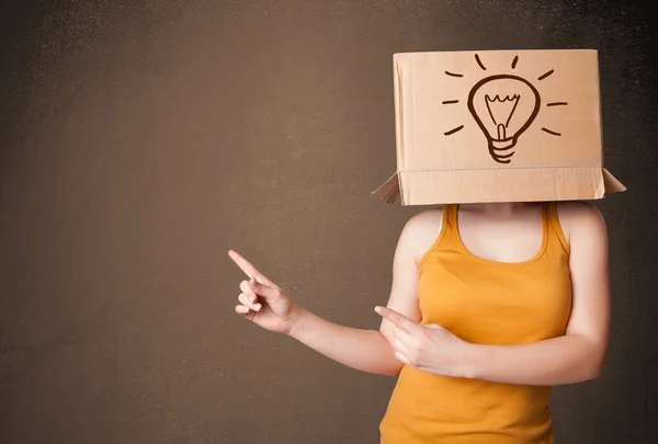 Jovem mulher gesticulando com uma caixa de papelão na cabeça com ligh — Fotografia de Stock