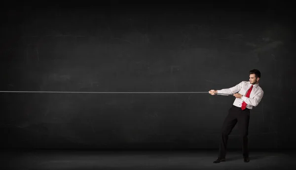 Businessman pulling rope on grey background — Stock Photo, Image