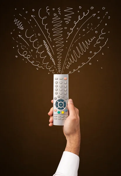 Hand with remote control and curly lines — Stock Photo, Image