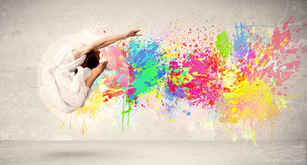 Happy teenager jumping with colorful ink splatter on urban backg — Stock Photo, Image