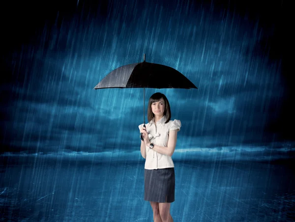 Affärskvinna stående i regnet med ett paraply — Stockfoto
