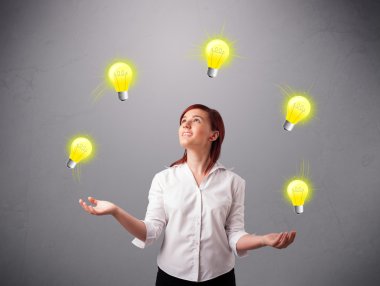 Genç bayan ayakta ve ampullerle hokkabazlık yapıyor.