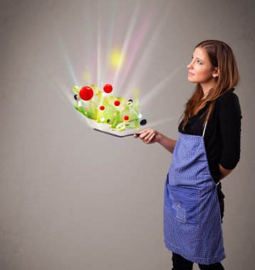 Genç bir kadın taze sebze pişiriyor.