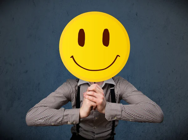 Empresário segurando um emoticon rosto sorridente — Fotografia de Stock