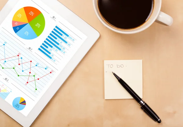 Tablet pc shows charts on screen with a cup of coffee on a desk — Stock Photo, Image