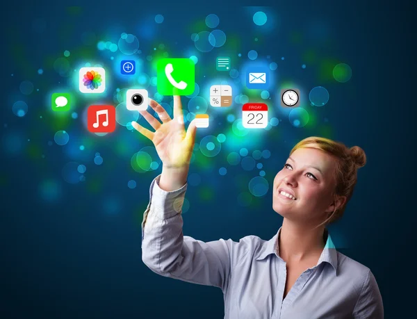 Young businesswoman pressing colorful mobile app icons with boke — Stock Photo, Image