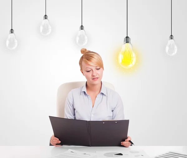 Mulher de negócios sentada à mesa com lâmpadas ideia — Fotografia de Stock