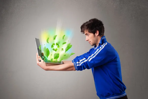 Casual boy holding laptop with recycle and environmental symbols — Stock Photo, Image