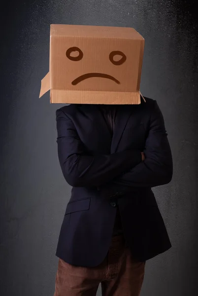 Young man with a brown cardboard box on his head with sad face — Stock Photo, Image