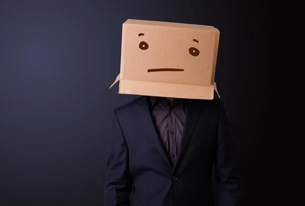 Young man gesturing with a cardboard box on his head with straig — Stock Photo, Image