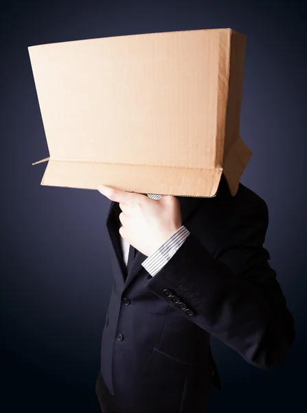 İş adamı kafasında karton bir kutuyla el kol hareketi yapıyor. — Stok fotoğraf