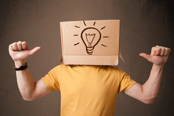 Joven haciendo gestos con una caja de cartón en la cabeza con luz — Foto de Stock