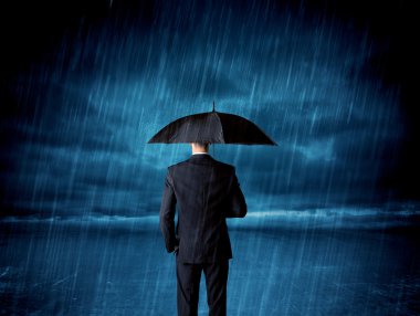 Business man standing in rain with an umbrella clipart