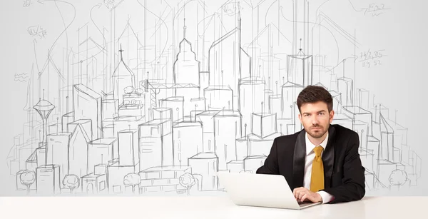 Geschäftsmann sitzt am weißen Tisch mit handgezeichneten Gebäuden — Stockfoto