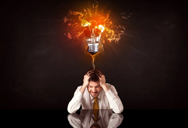 Businessman sitting under a blowing idea bulb — Stock Photo, Image