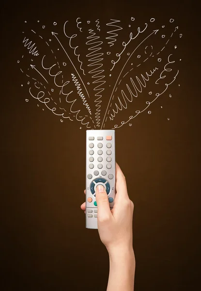 Hand with remote control and curly lines — Stock Photo, Image