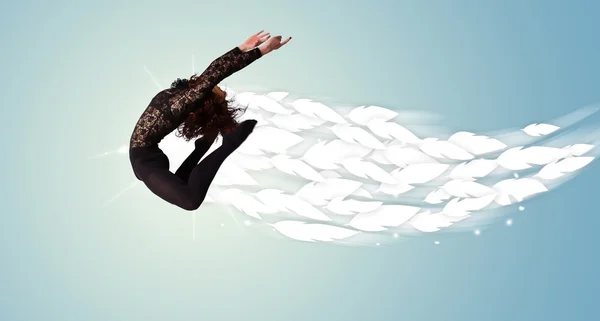Healthy young woman jumping with feathers around her — Stock Photo, Image