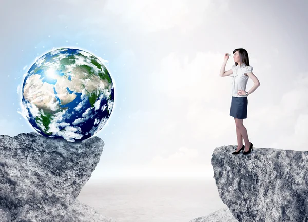 Businesswoman on rock mountain with a globe — Stock Photo, Image
