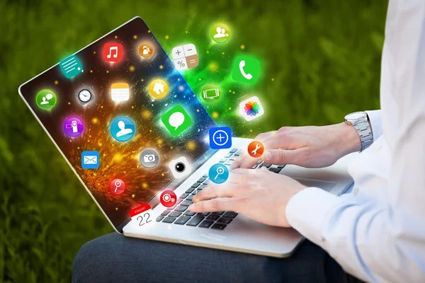 모바일 앱 아이콘과 심볼이 있는 현대 노트북을 누르는 손 — 스톡 사진
