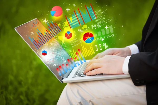 Hand typing on modern laptop notebook computer with graph icons — Stock Photo, Image