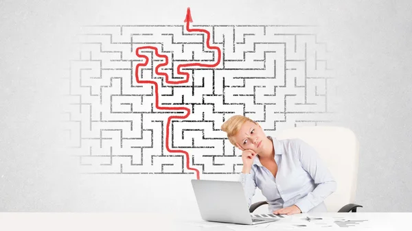 Business woman at desk with labyrinth and arrow — Stock Photo, Image