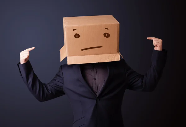 Joven haciendo gestos con una caja de cartón en la cabeza con straig — Foto de Stock