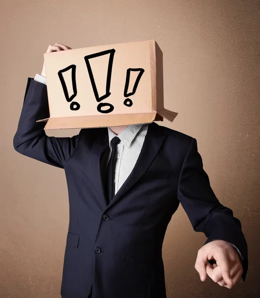 Businessman gesturing with a cardboard box on his head with excl — Stock Photo, Image