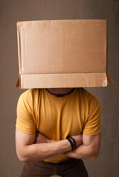 Young man gesturing with a cardboard box on his head — Stock Photo, Image