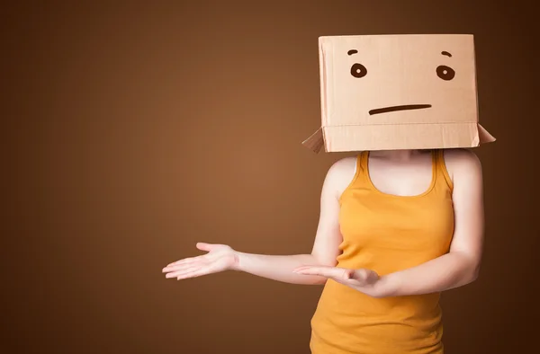 Young girl gesturing with a cardboard box on her head with strai — Stock Photo, Image