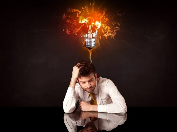 Businessman sitting under a blowing idea bulb — Stock Photo, Image